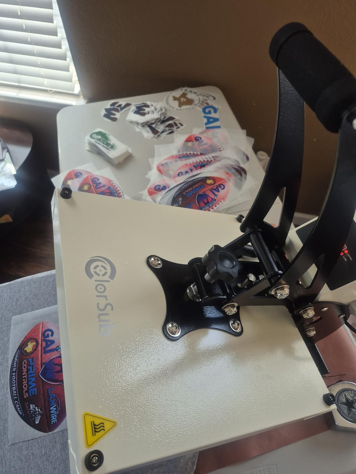White ColorSub heat press open above football-shaped transfers on the slide-out platen