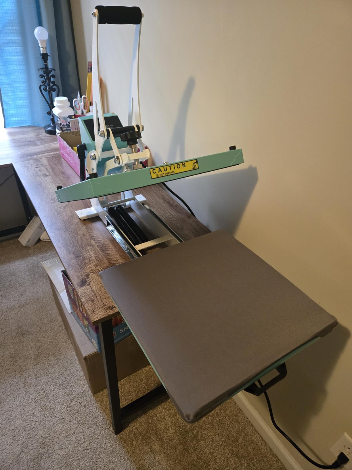 ColorSub heat press opened with its gray lower platen extended over a narrow worktable